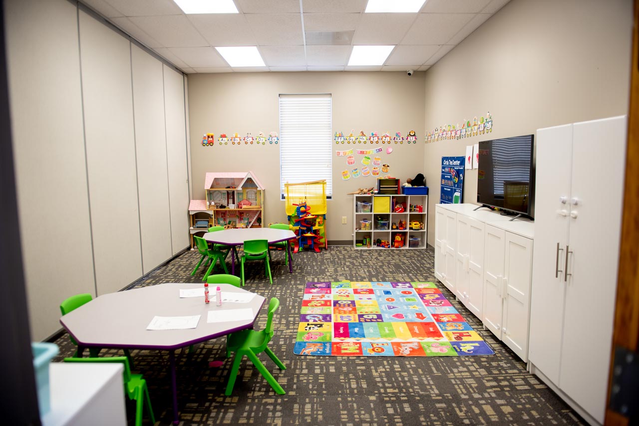 A bright pleasant room with two small tables and a shelf full of toys at Carolina Therapeutics Academy in Rock Hill, SC
