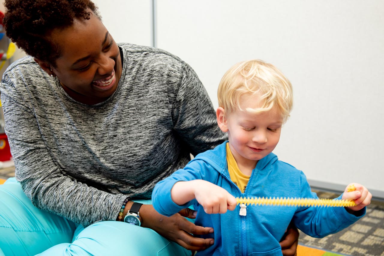 A smiling instructor playing with a student at special needs preschool