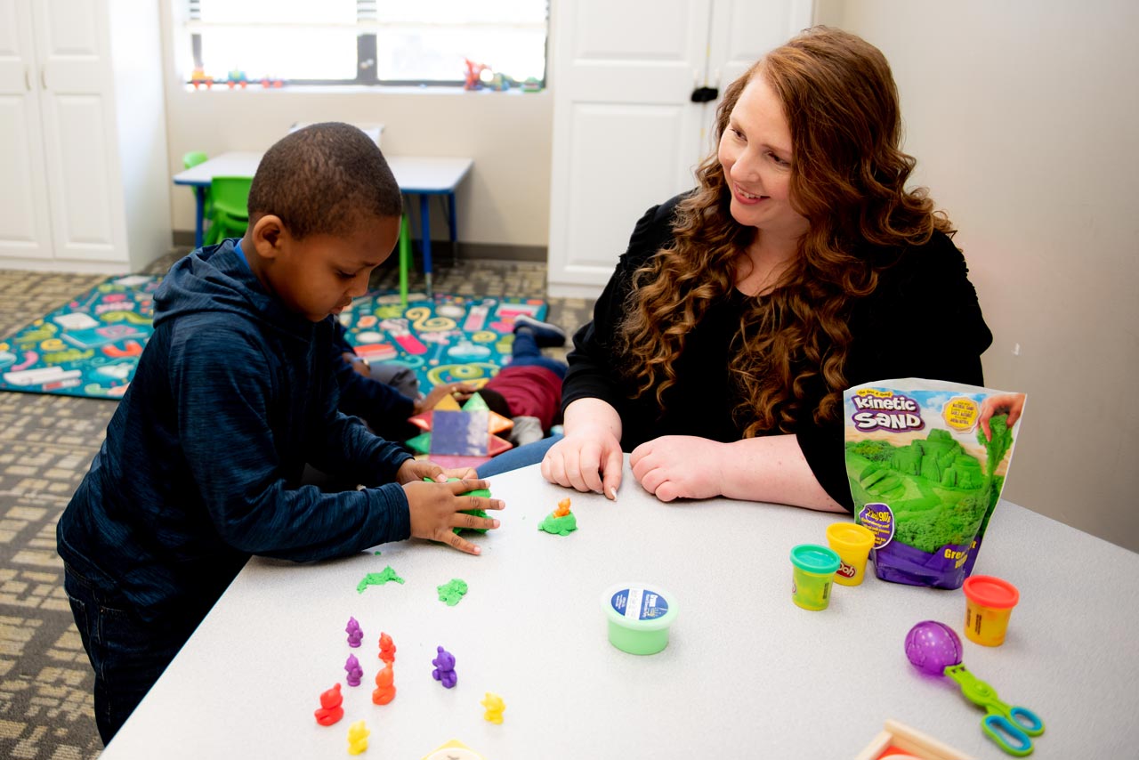 A preschool teacher with red curly hair plays with a boy at special needs school in Rock Hill, SC
