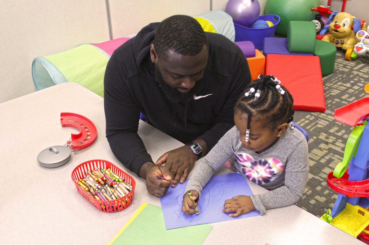 A therapist helps a young girl draw with crayons at Carolina Therapeutics Academy in Rock Hill, SC