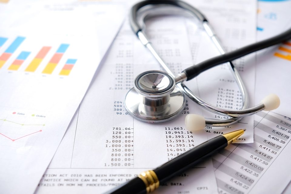 A stethoscope sitting a top of a pile of medical billing records