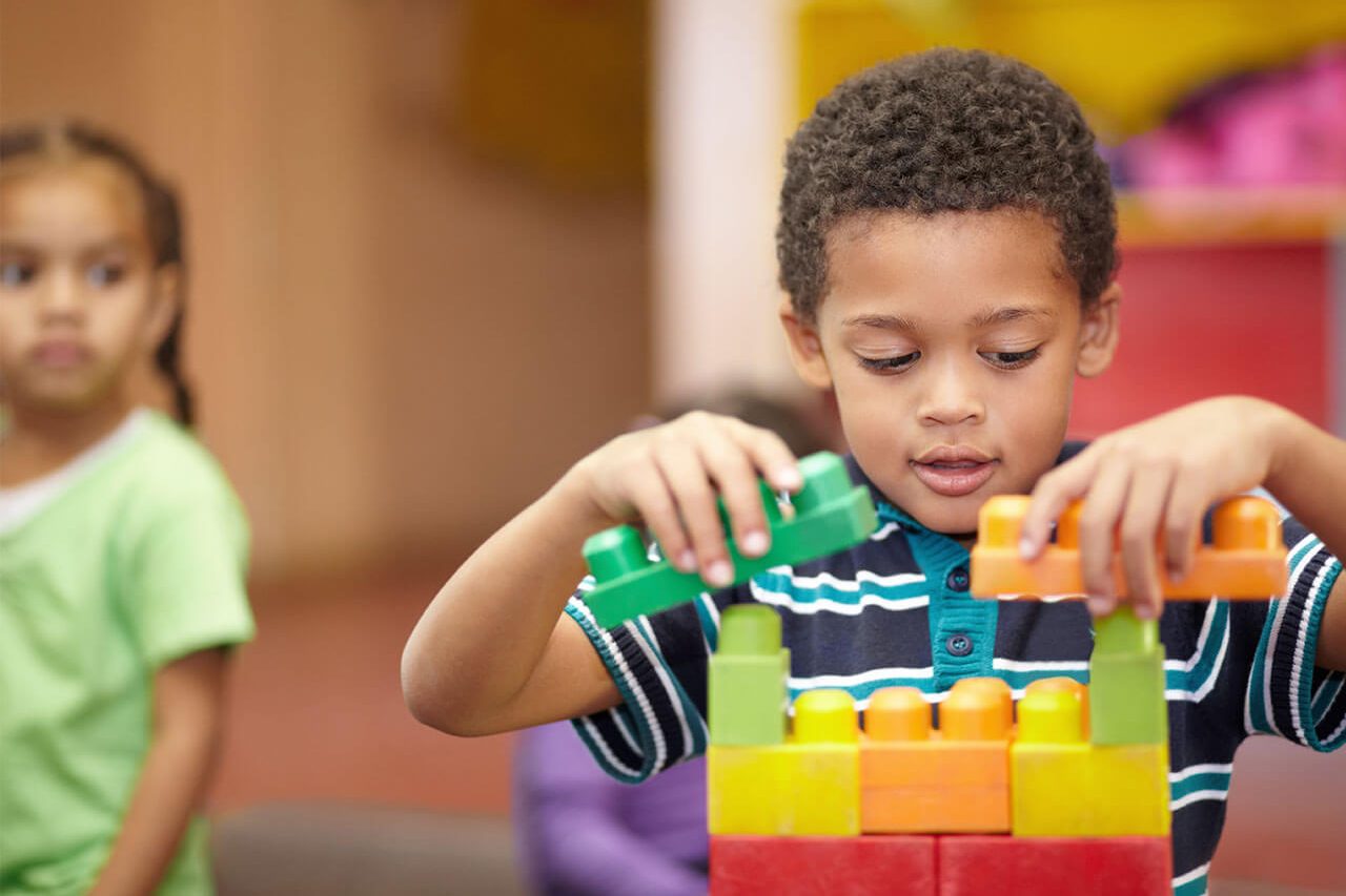 A young boy plays with colorful building blocks at a special needs school