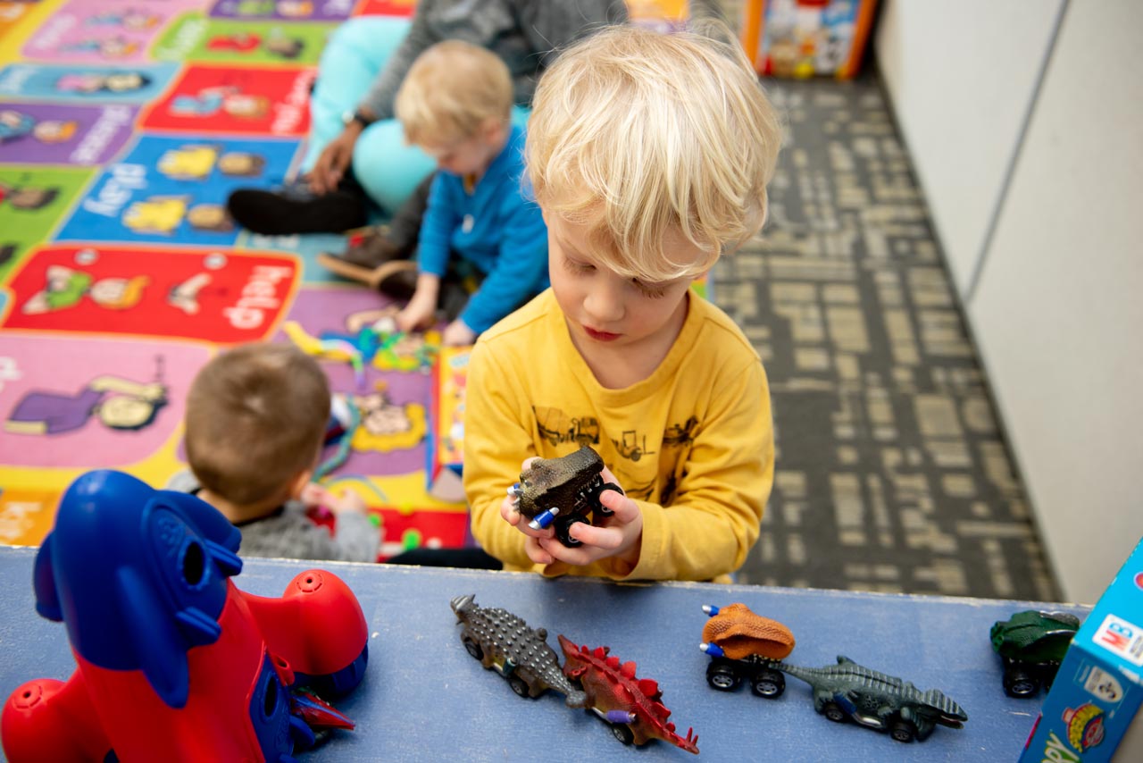 Young boy in yellow shirt playing with a toy car at at Carolina Therapeutics Academy a special needs preschool in Rock Hill, SC