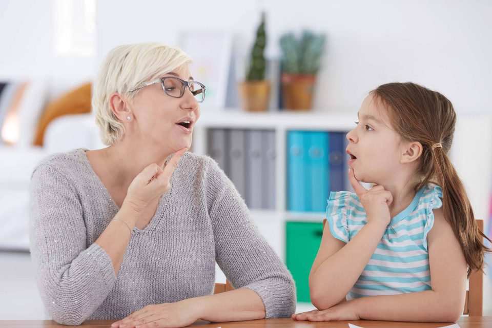 Female speech therapist providing speech therapy to a young girl