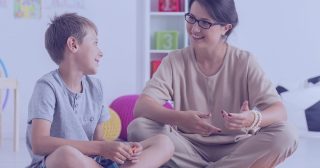 A female therapist sits with a young boy during a session at a therapeutic day school