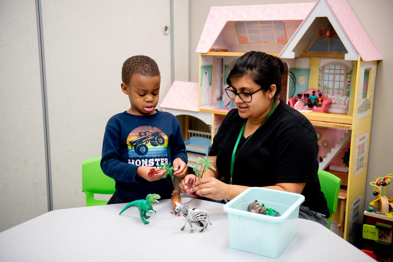 Young boy plays with plant and animal figurines at special needs preschool Carolina Therapeutics Academy